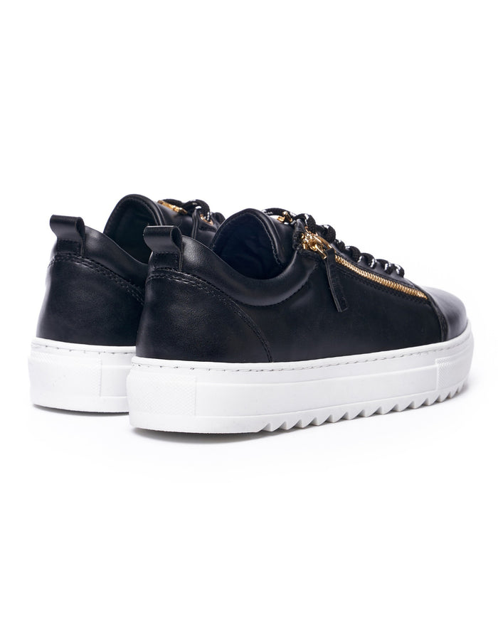 Martin Valen close three-quarter front view of black sneaker pair showing gold zipper and white sole